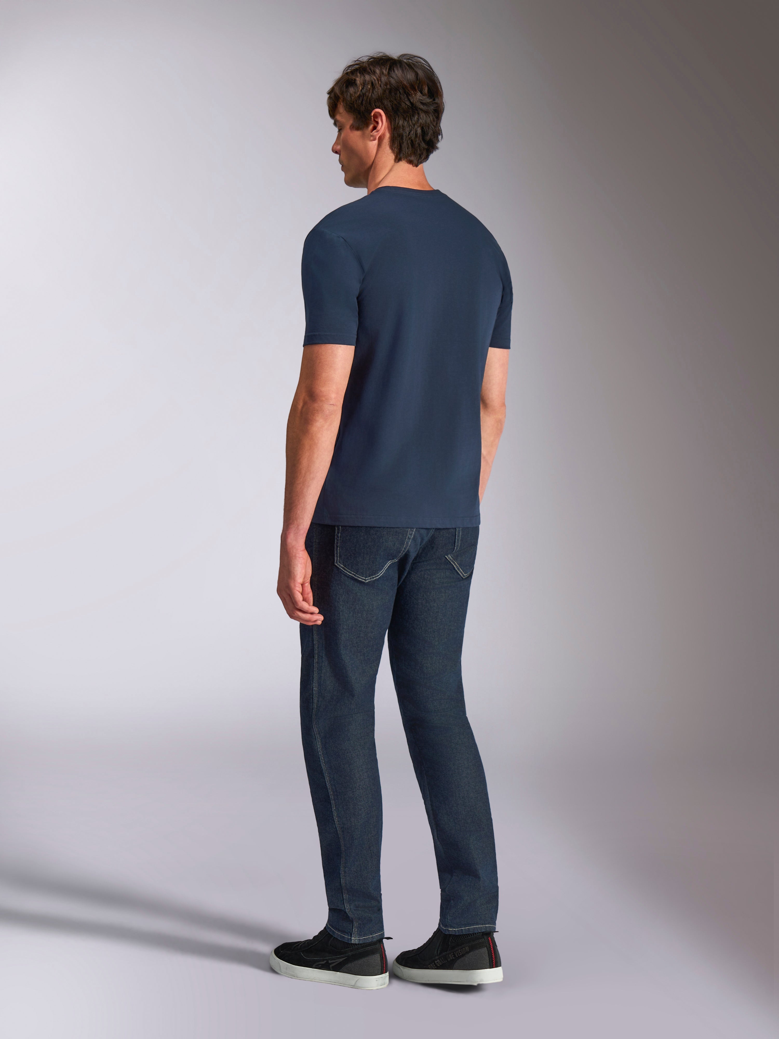 Alpinestars Ageless Shadow CSF Tee, maglietta a maniche corte, navy, vista posteriore su modello, indossata con jeans in denim scuro e sneakers nere, stile casual streetwear