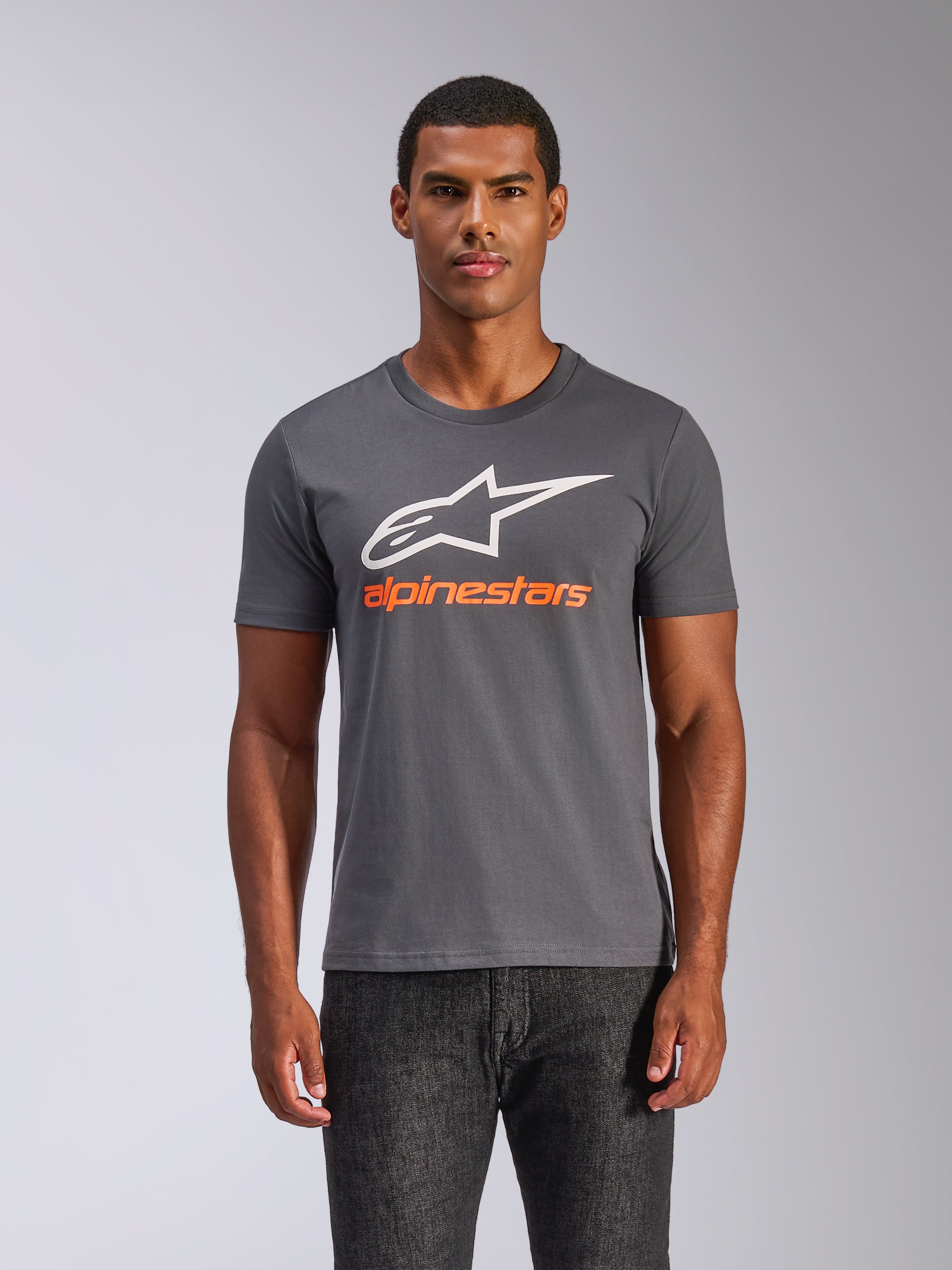 Alpinestars Always 2.0 CSF Tee, maglietta a maniche corte, grigio antracite, grande logo A-star bianco con scritta Alpinestars arancione, indossata da un uomo, streetwear casual ispirato al motorsport