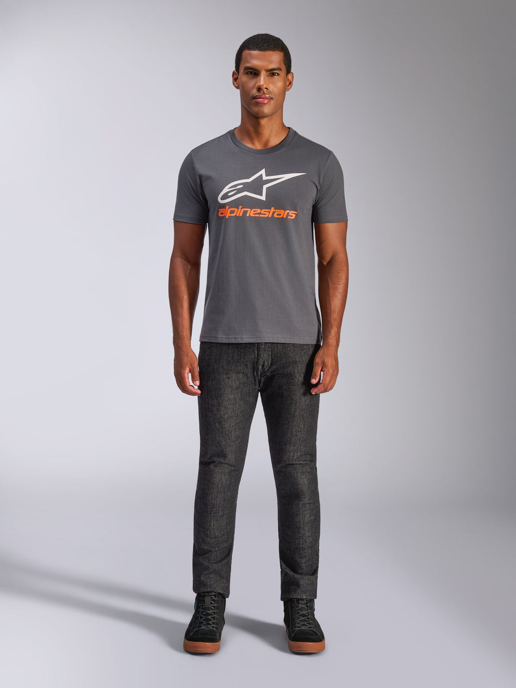 Alpinestars Always 2.0 CSF Tee, maglietta a maniche corte, grigio antracite con logo bianco e testo arancione, indossata da un modello con jeans scuri, streetwear casual motorsport