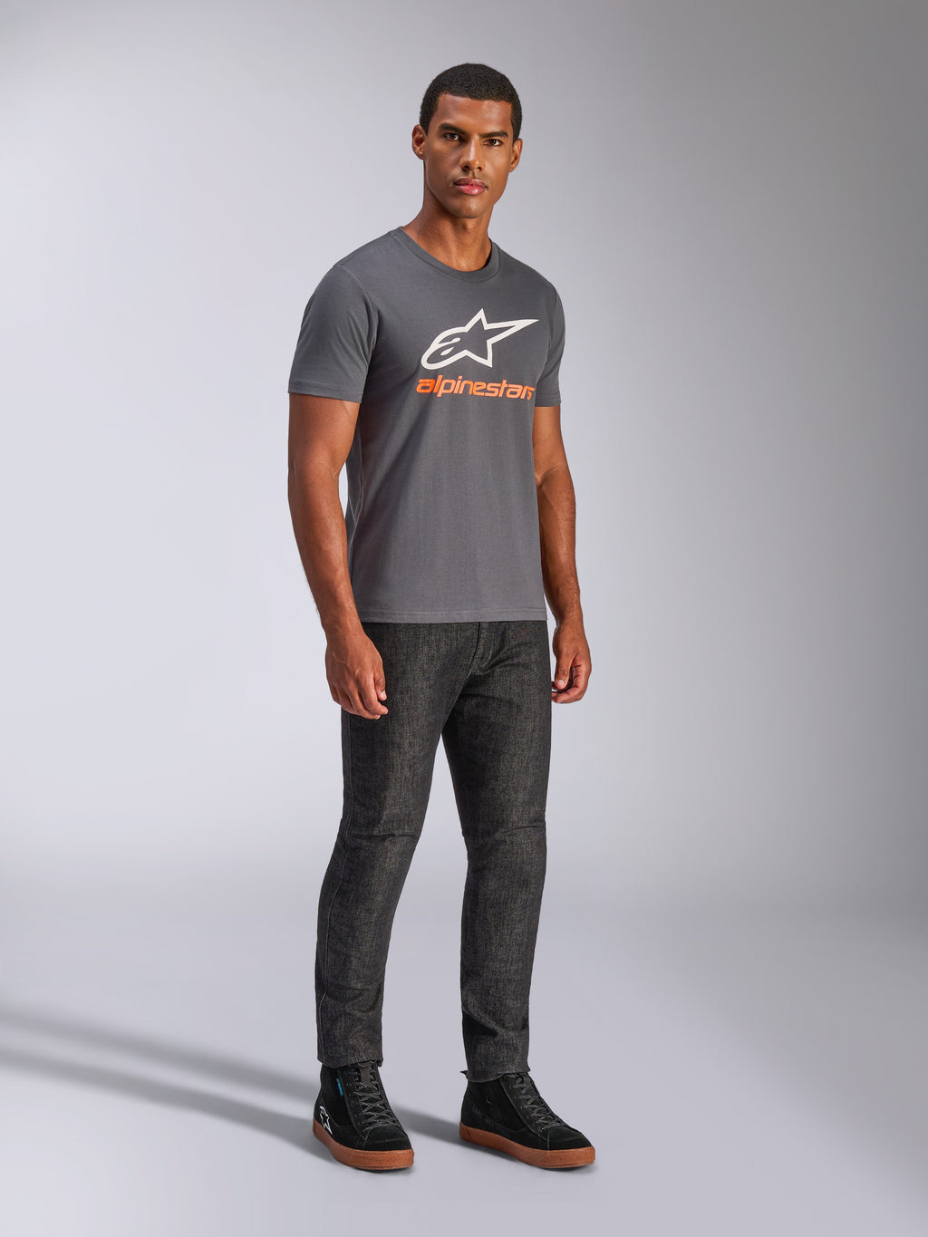 Alpinestars Always 2.0 CSF Tee, t-shirt a maniche corte, grigio antracite, logo A-star bianco con branding arancione, streetwear casual motorsport indossata con jeans scuri e sneakers nere