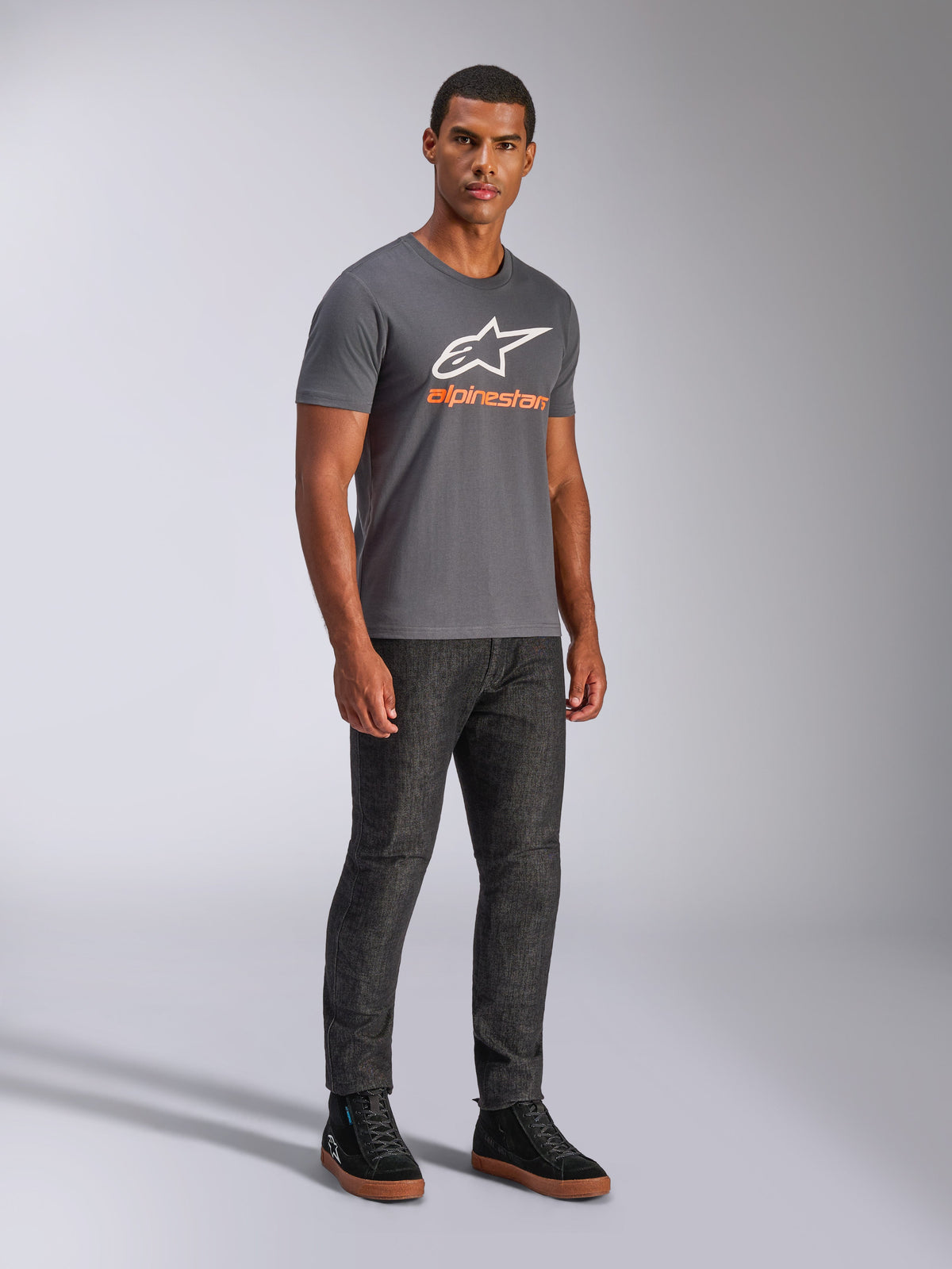 Alpinestars Always 2.0 CSF Tee, t-shirt a maniche corte, grigio antracite, logo A-star bianco con branding arancione, streetwear casual motorsport indossata con jeans scuri e sneakers nere