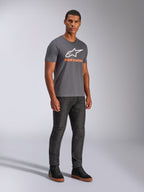 Alpinestars Always 2.0 CSF Tee, t-shirt a maniche corte, grigio antracite, logo A-star bianco con branding arancione, streetwear casual motorsport indossata con jeans scuri e sneakers nere