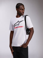 Alpinestars Always 2.0 CSF Tee, t-shirt a maniche corte, bianca, logo a stella nero e scritta Alpinestars rossa, indossata da un modello con borsa a tracolla nera, abbigliamento sportivo casual motorsport