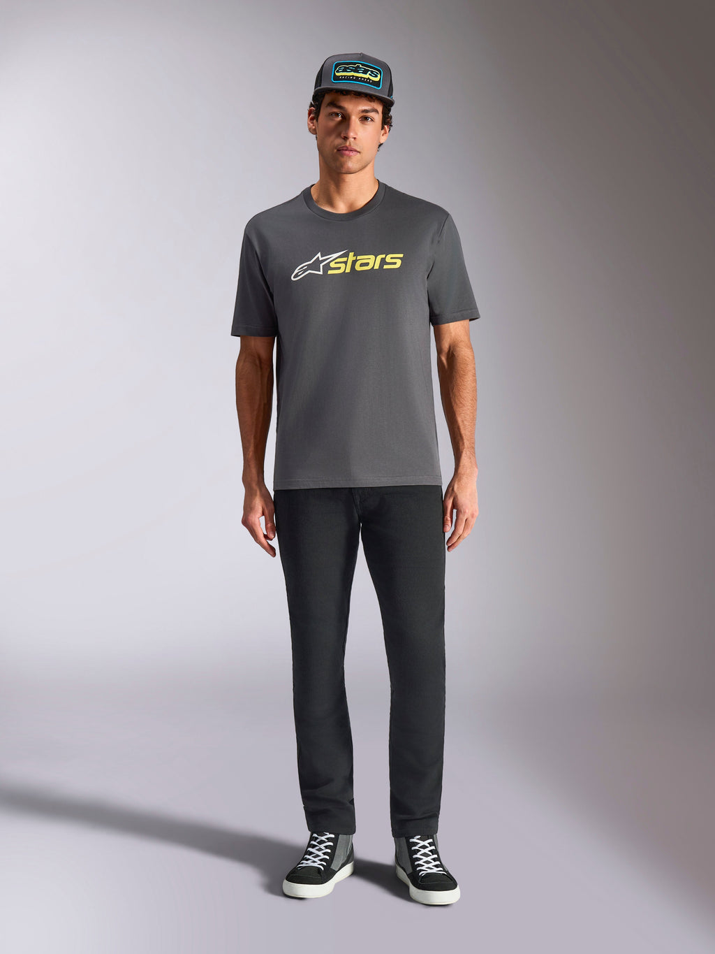 Alpinestars Blaze 2.0 CSF Tee, maglietta a maniche corte, grigio antracite con logo bianco e giallo hi-vis, indossata con pantaloni neri e cappellino trucker coordinato, stile casual motorsport