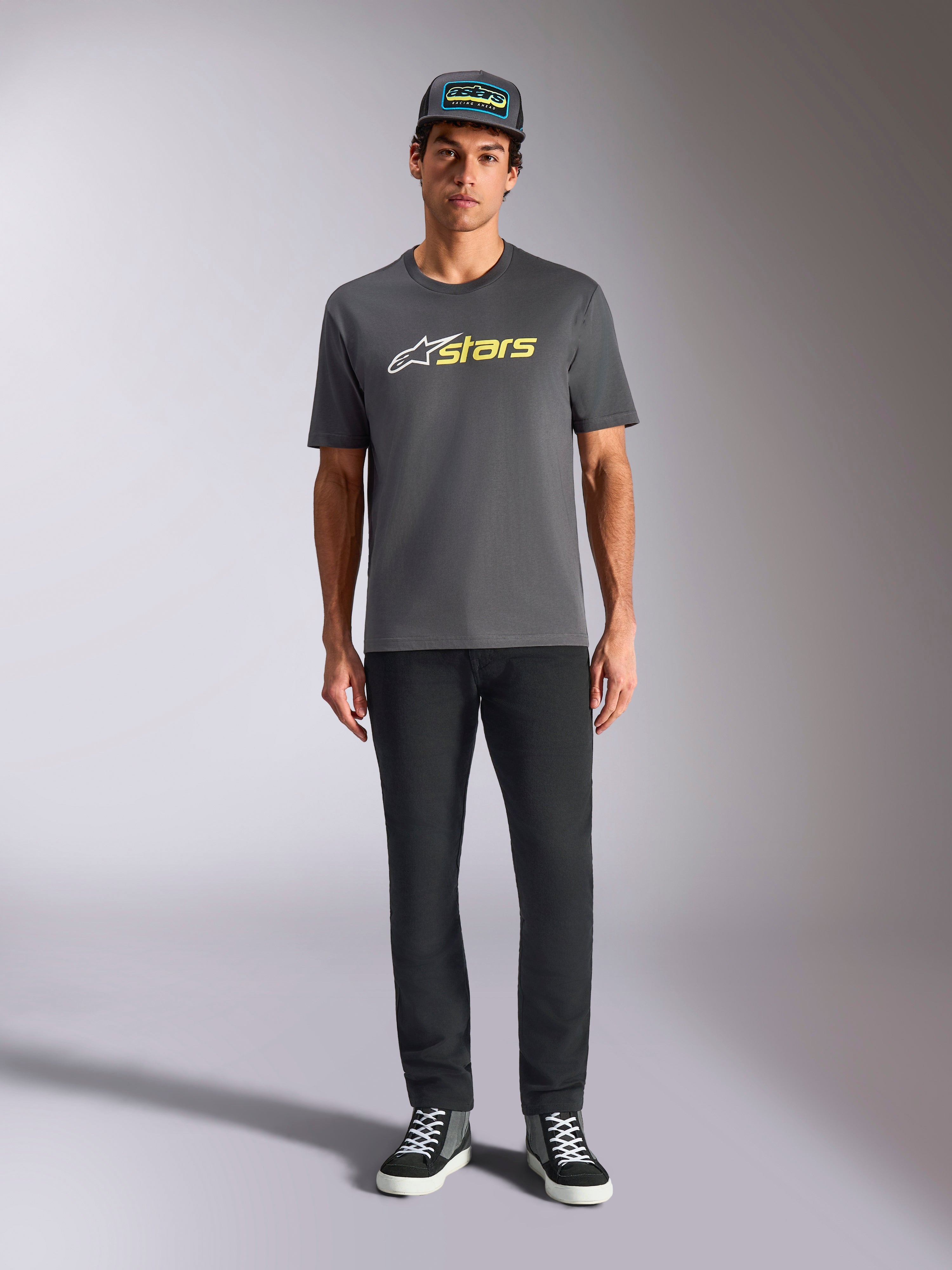 Alpinestars Blaze 2.0 CSF Tee, maglietta a maniche corte, grigio antracite con logo bianco e giallo hi-vis, indossata con pantaloni neri e cappellino trucker coordinato, stile casual motorsport
