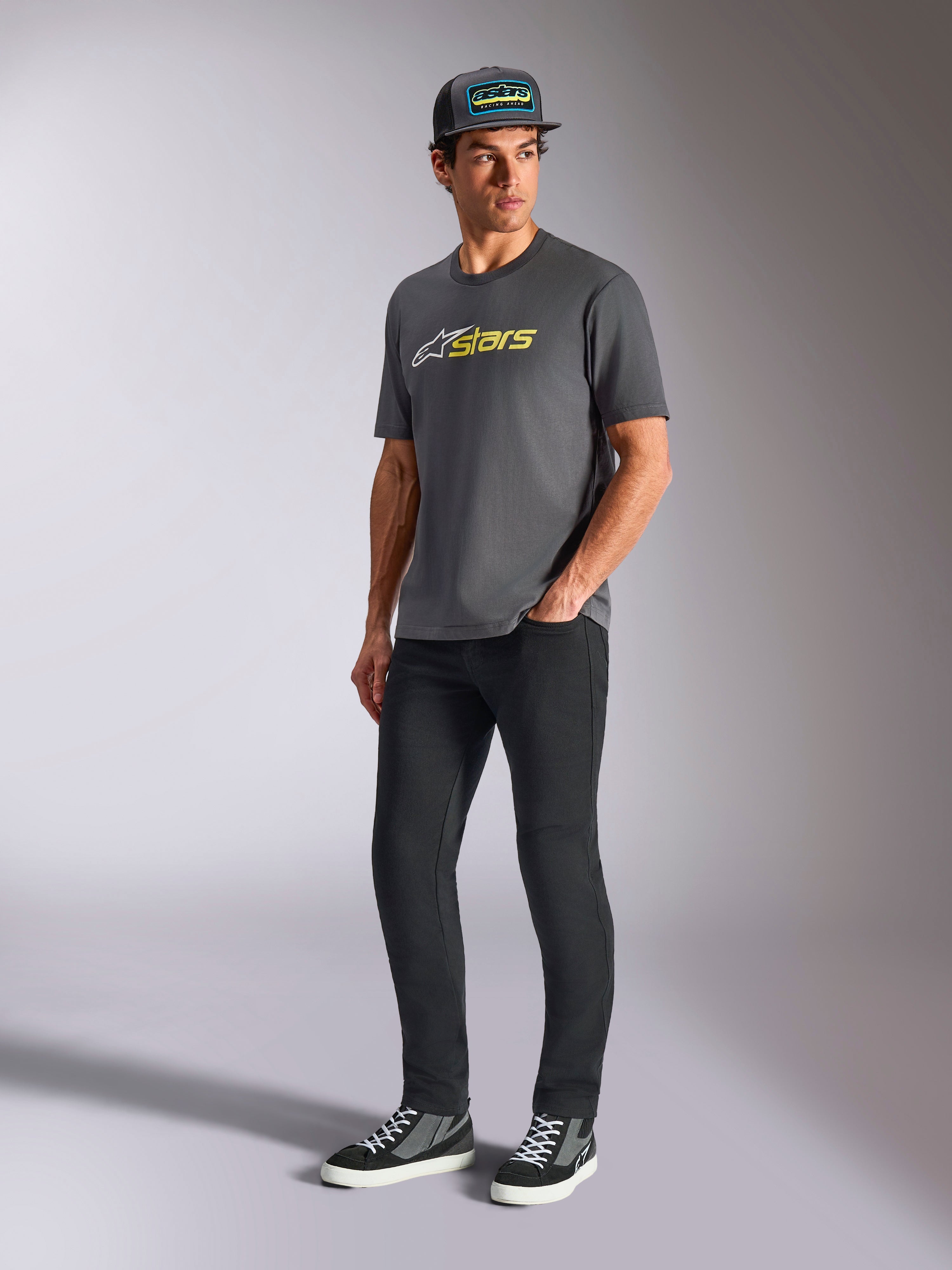 Alpinestars Blaze 2.0 CSF Tee, t-shirt a maniche corte, grigio antracite con logo bianco e giallo fluo, indossata da un modello con cappello e pantaloni neri, abbigliamento lifestyle motorsport casual
