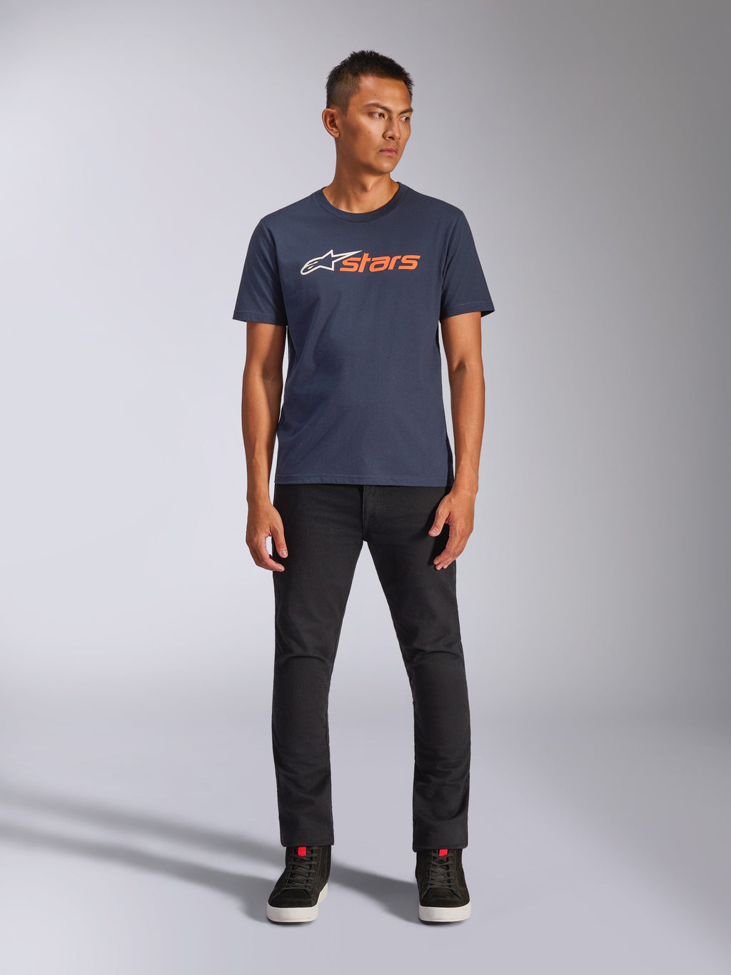Alpinestars Blaze 2.0 CSF Tee, maglietta a maniche corte, blu navy con logo Astars bianco e arancione, indossata con pantaloni neri e sneakers nere, streetwear casual ispirato al motorsport