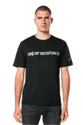 Alpinestars Linear Wordmark 2.0 CSF Tee, maglietta a maniche corte, nero, marchio lineare grigio sul petto e logo Ageless rosso sulla manica, indossata da un modello con jeans scuri, streetwear casual ispirato al motorsport
