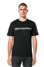 Alpinestars Linear Wordmark 2.0 CSF Tee, maglietta a maniche corte, nero, marchio lineare grigio sul petto e logo Ageless rosso sulla manica, indossata da un modello con jeans scuri, streetwear casual ispirato al motorsport