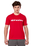 Alpinestars Linear Wordmark 2.0 CSF Tee, maglietta a maniche corte, rossa, logo lineare bianco sul petto e logo Ageless sulla manica, indossata da un modello con pantaloni della tuta grigi, streetwear casual ispirato al motorsport
