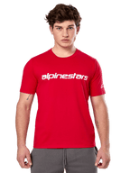 Alpinestars Linear Wordmark 2.0 CSF Tee, maglietta a maniche corte, rossa, logo lineare bianco sul petto e logo Ageless sulla manica, indossata da un modello con pantaloni della tuta grigi, streetwear casual ispirato al motorsport