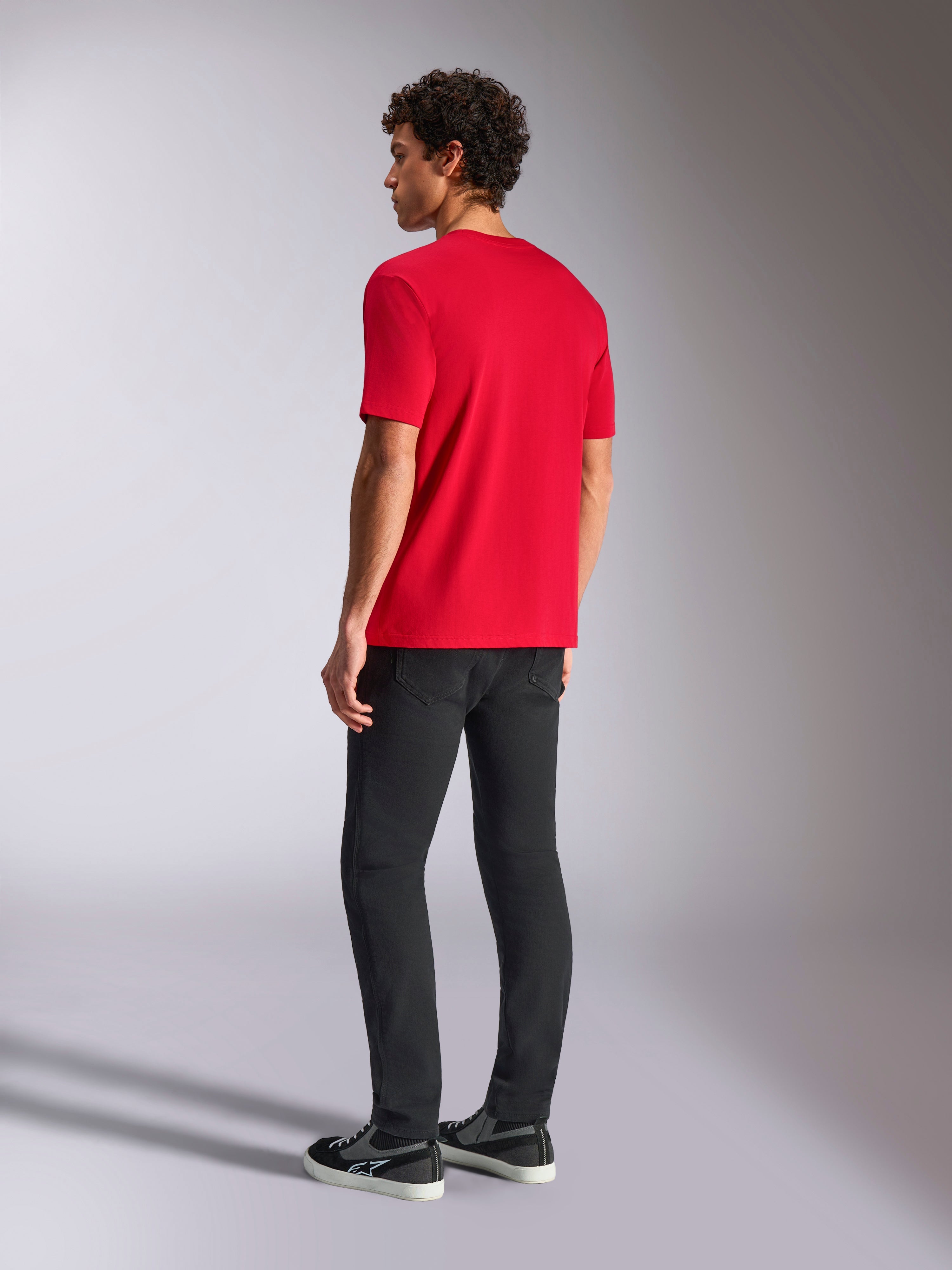 Alpinestars Ride 4.0 CSF Tee, T-shirt a maniche corte, rossa, vista posteriore su modello che indossa pantaloni neri e sneakers, streetwear casual da motorsport