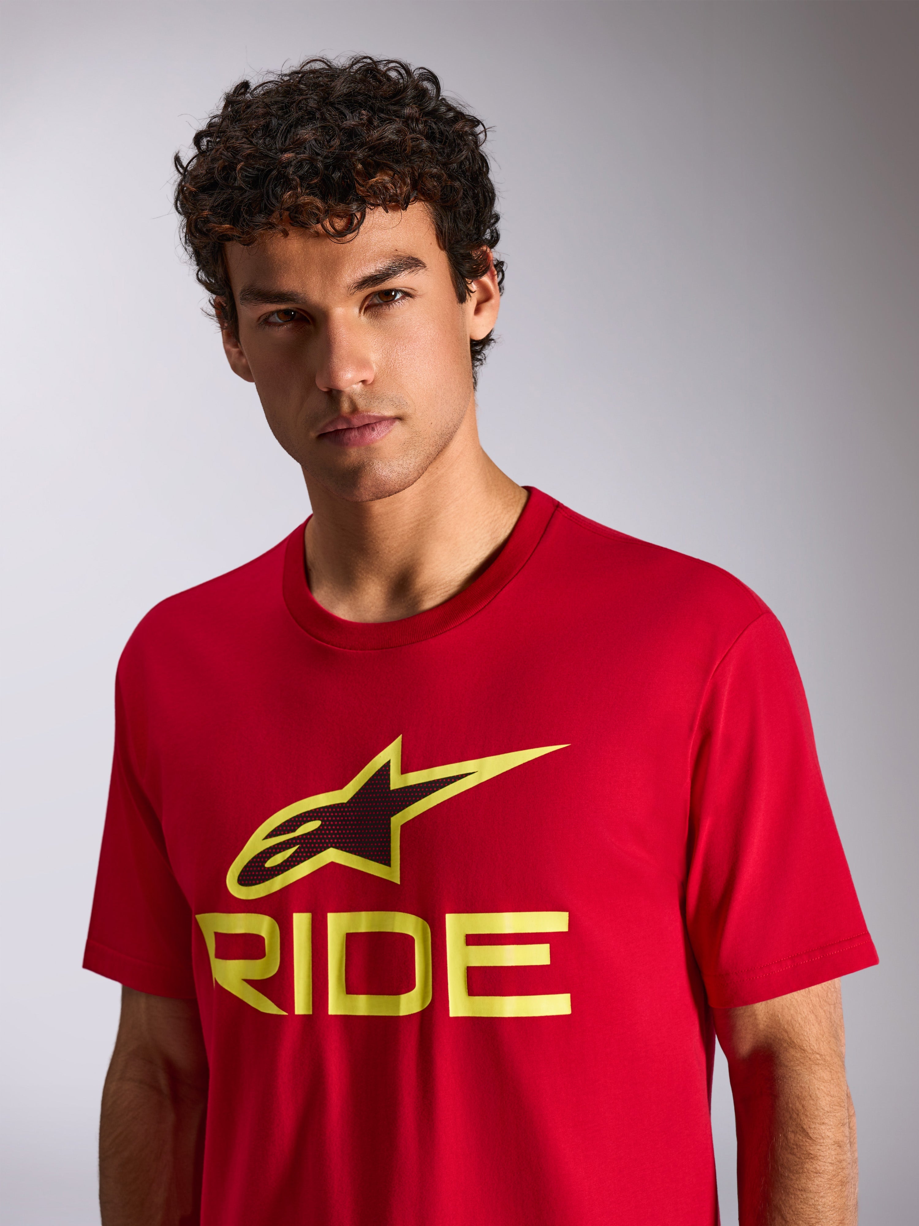 Alpinestars Ride 4.0 CSF Tee, t-shirt a maniche corte, rossa con logo Ride giallo fluo e nero, indossata da un modello, streetwear casual motorsport