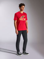 Alpinestars Ride 4.0 CSF Tee, t-shirt a maniche corte, rossa con logo frontale giallo e nero, indossata con pantaloni neri e sneakers, abbigliamento casual motorsport streetwear