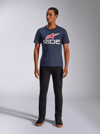 Alpinestars Ride 4.0 CSF Tee, t-shirt a maniche corte, blu navy con logo Alpinestars a stella rosso e scritta 'RIDE' bianca sul petto, indossata da un modello con pantaloni neri e sneaker nere, streetwear casual ispirato al motorsport