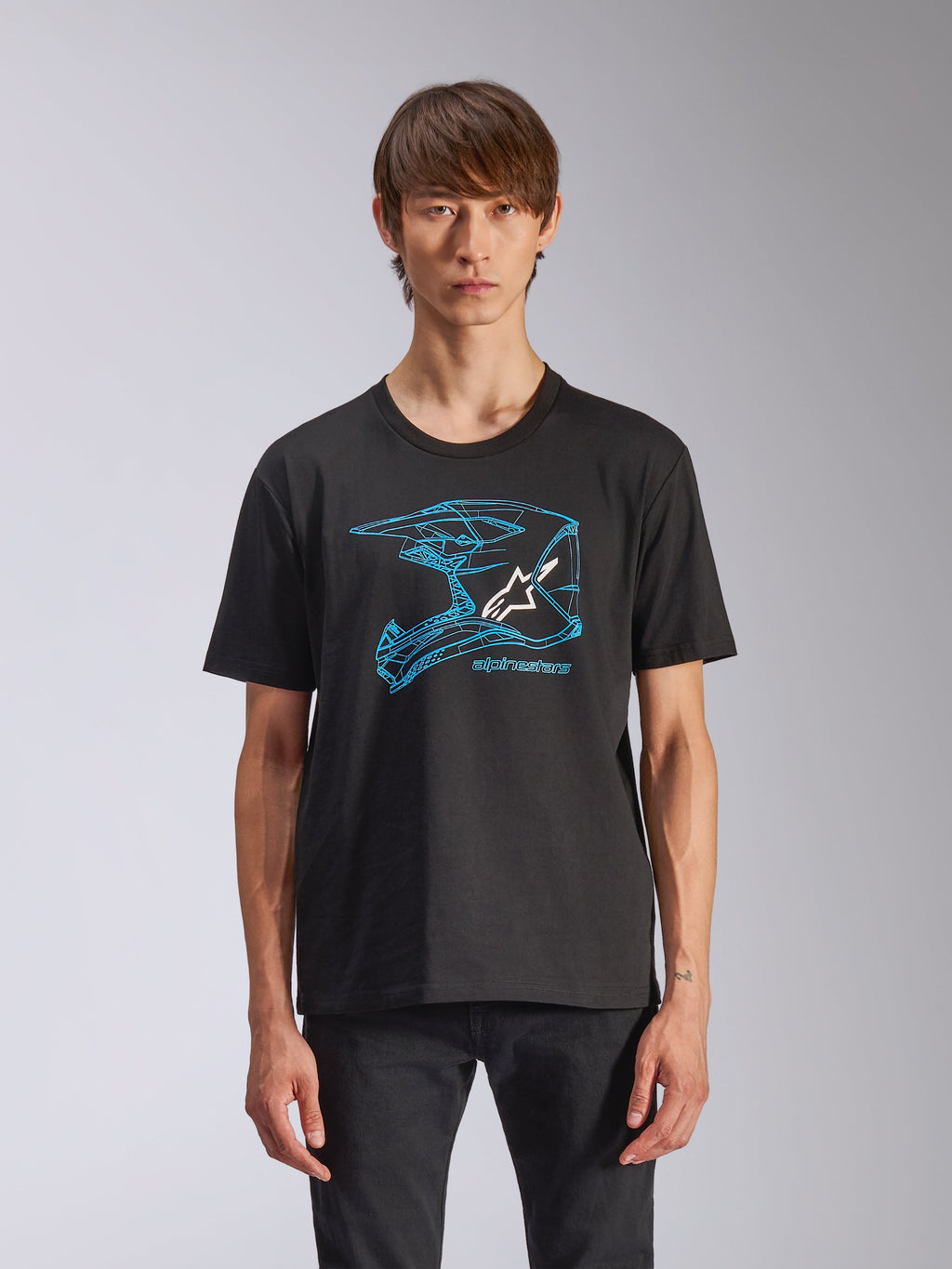 Alpinestars CSF Tee, t-shirt a maniche corte, nera, grafica blu del casco da motocross con logo Astars bianco, streetwear casual ispirato al motorsport indossata da un modello