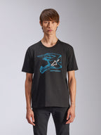 Alpinestars CSF Tee, t-shirt a maniche corte, nera, grafica blu del casco da motocross con logo Astars bianco, streetwear casual ispirato al motorsport indossata da un modello