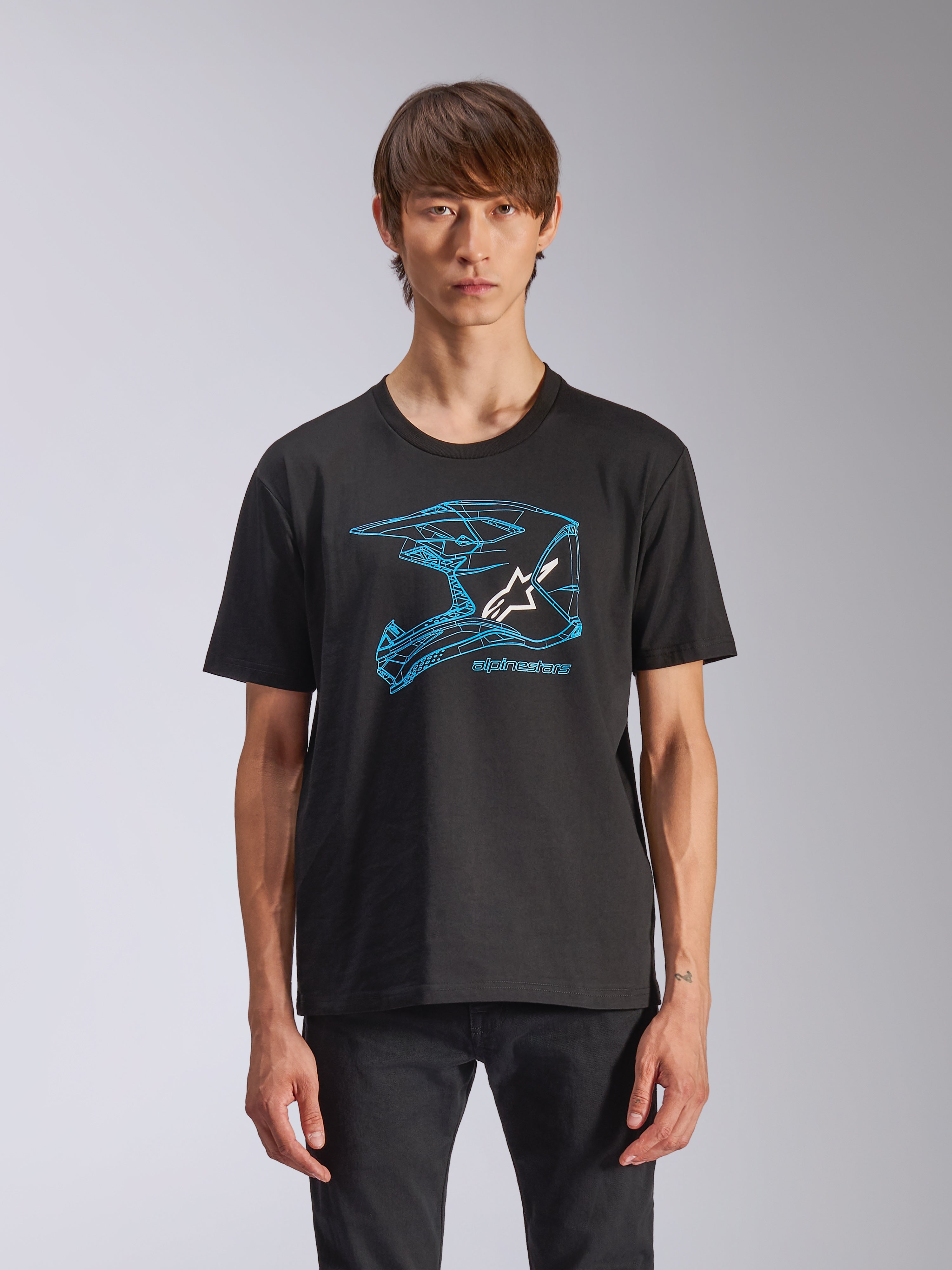 Alpinestars CSF Tee, t-shirt a maniche corte, nera, grafica blu del casco da motocross con logo Astars bianco, streetwear casual ispirato al motorsport indossata da un modello