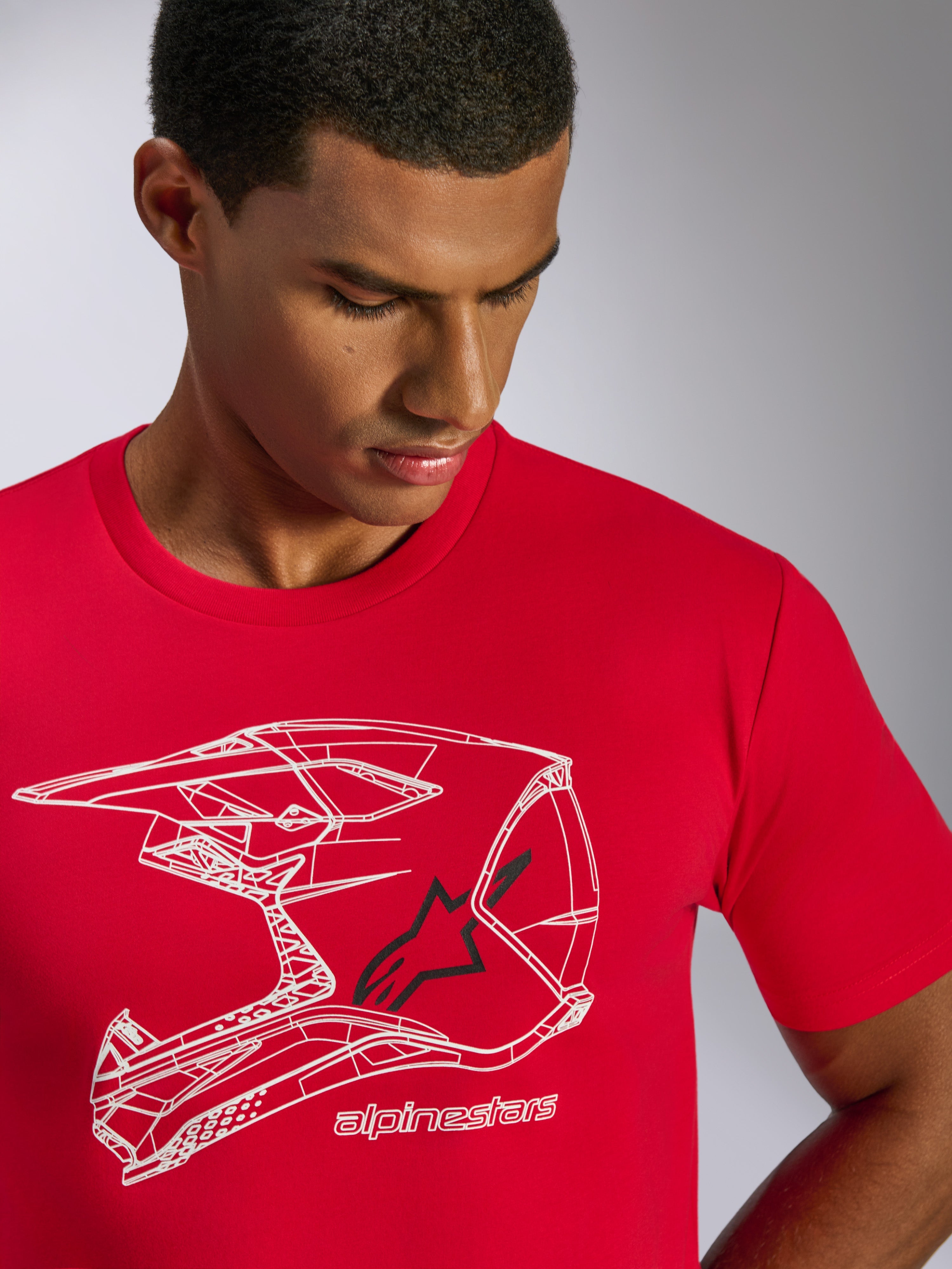 T-shirt Alpinestars CSF Tee, maglietta a maniche corte, rosso, grafica con profilo di casco MX bianco, logo a stella nero e nome del brand, indossata da un uomo, abbigliamento casual motorsport streetwear