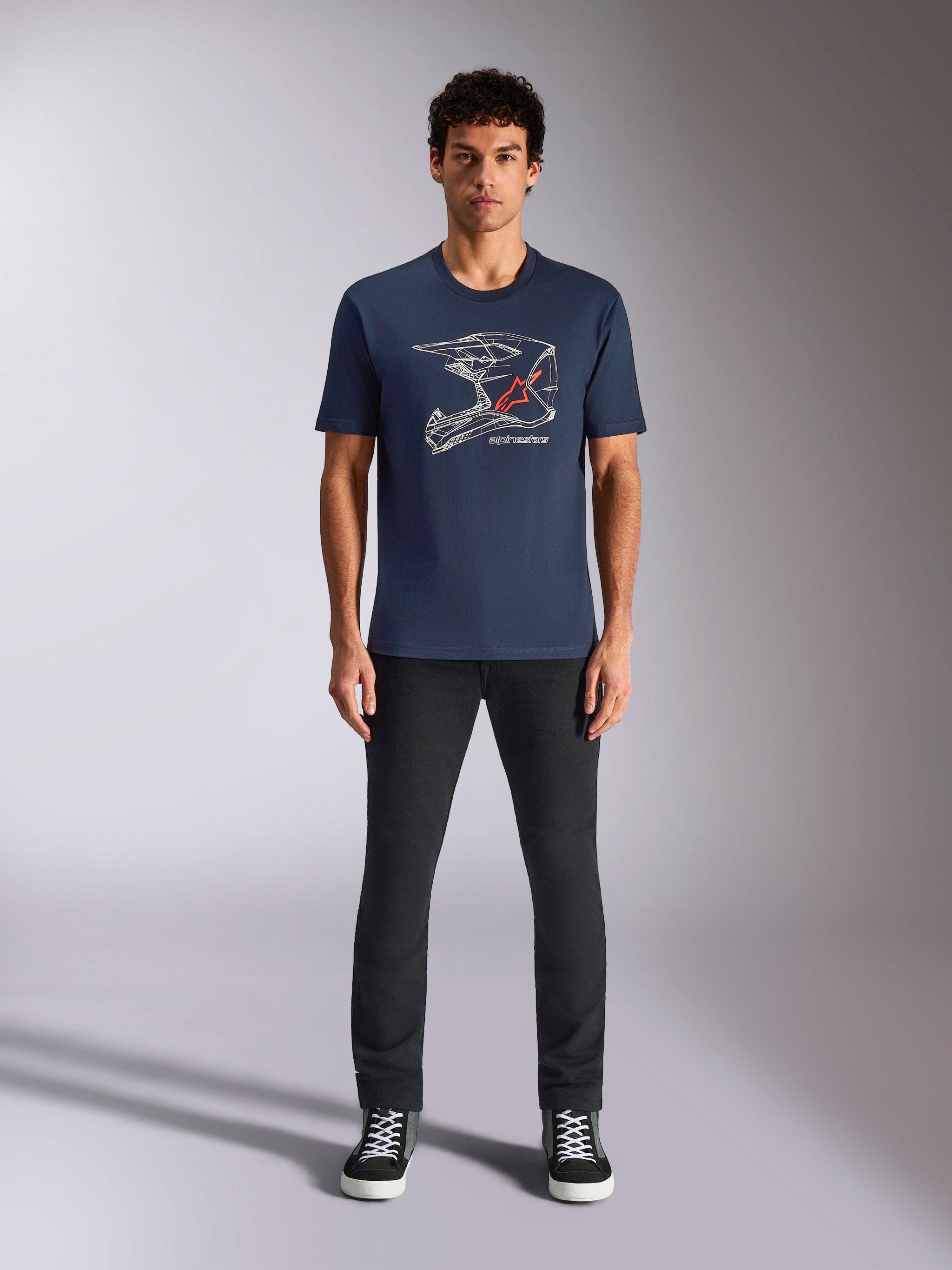 Alpinestars MX Helmet CSF Tee, t-shirt a maniche corte, blu navy, con grafica bianca di un casco da motocross e logo a stella rosso, indossata da un modello con pantaloni neri e sneakers, streetwear casual ispirato al motorsport