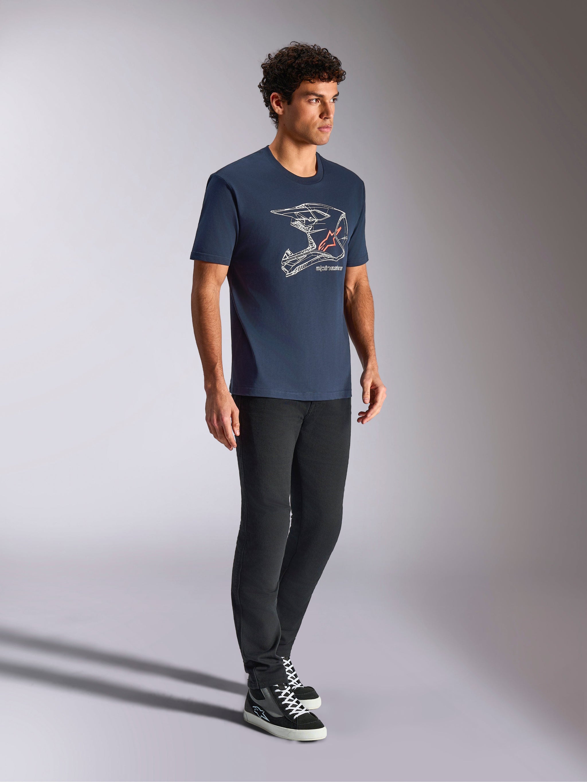 Alpinestars MX Helmet CSF Tee, t-shirt a maniche corte, blu navy, con grafica lineare bianca di un casco da motocross e logo a stella rosso, streetwear casual ispirato al motorsport indossato con pantaloni neri e sneaker alte