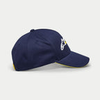 Alpinestars Par Hat, cappellino da baseball blu navy, vista laterale con ricamo del logo bianco e giallo, visiera curva con bordo sandwich giallo, copricapo casual strutturato