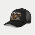 Alpinestars Heritage Patch Trucker Hat, nero, corona strutturata con visiera curva, grande patch frontale ricamata heritage con ruota alata e 'Racing Ahead Est. 1963', pannelli posteriori in rete nera con logo a stella laterale, copricapo casual motorsport lifestyle