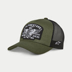 Cappello Alpinestars Heritage Patch Trucker, nero militare e verde oliva, visiera curva con corona strutturata, grande patch ricamata frontale con grafica di ruota di moto vintage e scritta 'Racing Ahead', retro in rete nera con logo Ageless bianco sul lato.
