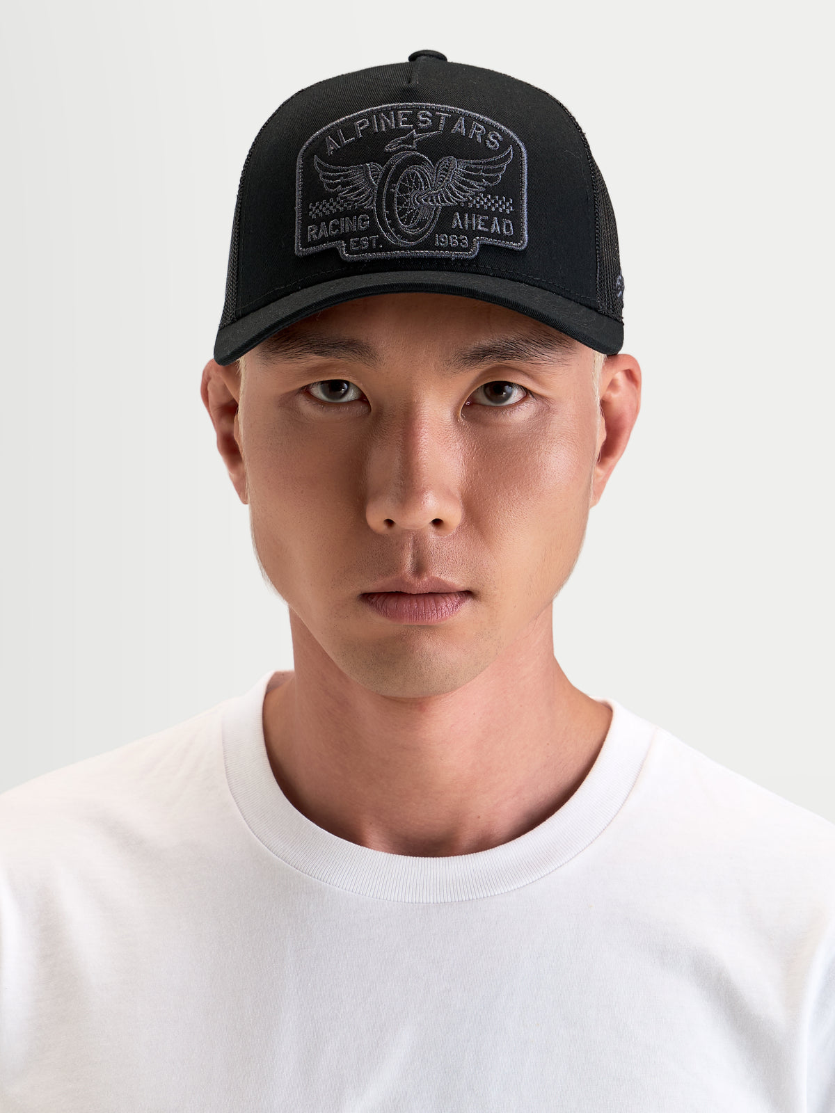 Alpinestars Cappello Heritage Patch, cappello trucker sportswear in nero e grigio, con visiera curva, corona strutturata, retro in rete e grande patch logo ricamata, indossato da un modello