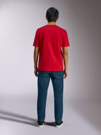 Alpinestars Ageless Shadow CSF Tee, vista posteriore della maglietta rossa a maniche corte, indossata con jeans in denim blu scuro e sneakers nere, abbigliamento casual motorsport streetwear