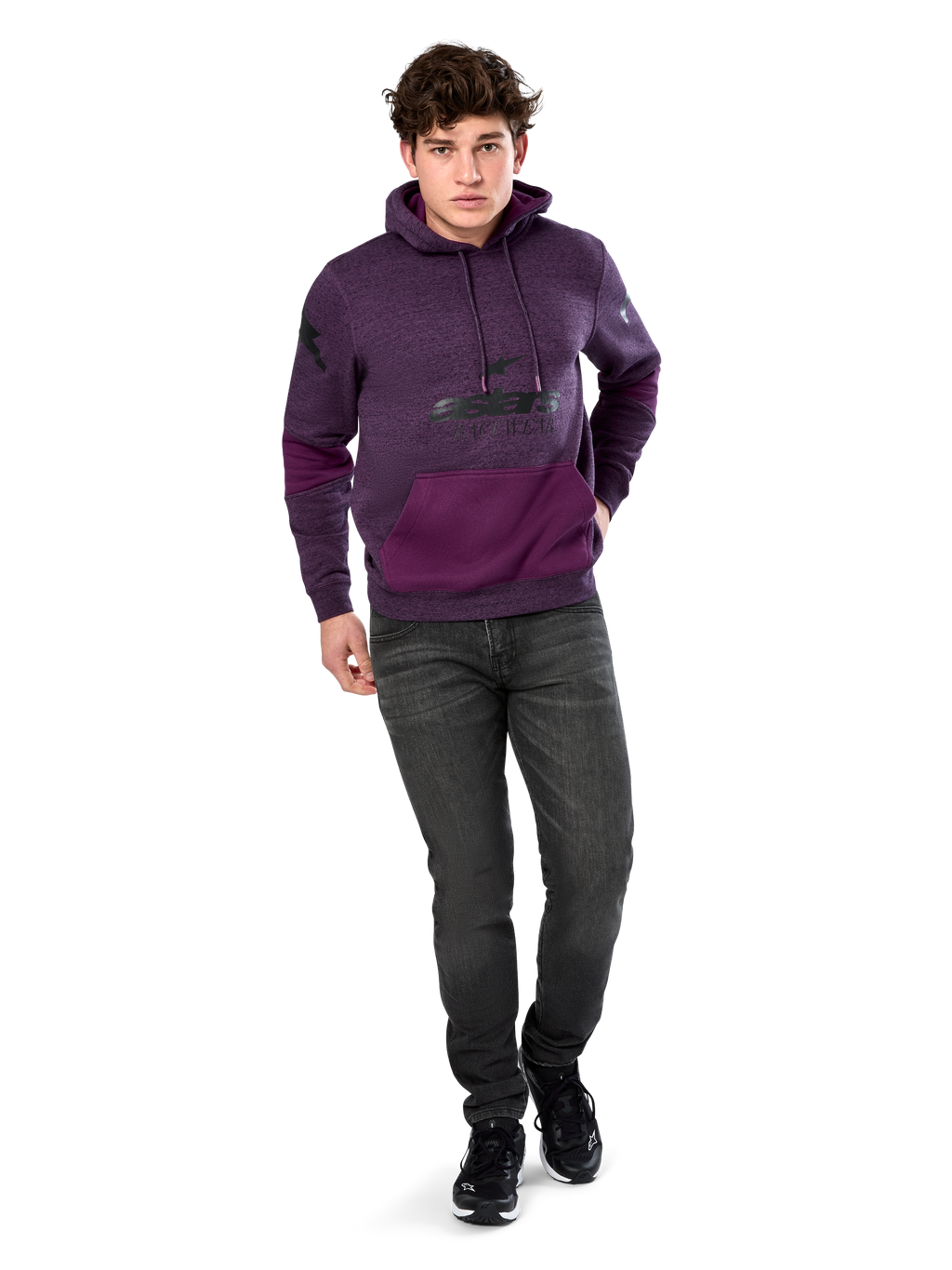 Alpinestars Perpetuate Hoodie, felpa con cappuccio, streetwear casual, pile viola mélange con inserti in tessuto viola scuro sulla tasca a marsupio e sulle maniche, logo nero sul petto, cappuccio con cordino, indossata da un modello con jeans grigio scuro e sneakers nere