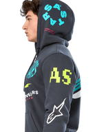 Felpa con cappuccio Alpinestars Variegate, pile grigio gunmetal con zip frontale, profilo laterale del modello, grafica multi-logo in giallo neon, azzurro e bianco, presenta il marchio 'AS' sulla manica e 'STARS' sul cappuccio, streetwear casual ispirato al motorsport