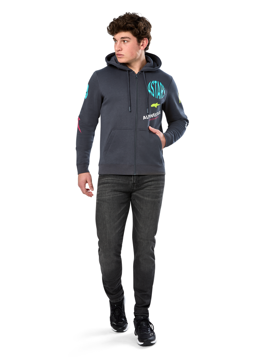 Alpinestars Variegate Hoodie, felpa in pile con zip frontale, grigio Gunmetal, indossata da un modello con jeans neri e sneakers, con marchio 'ASTARS' verde acqua e grafiche logo colorate su maniche e petto, streetwear casual ispirato al motorsport