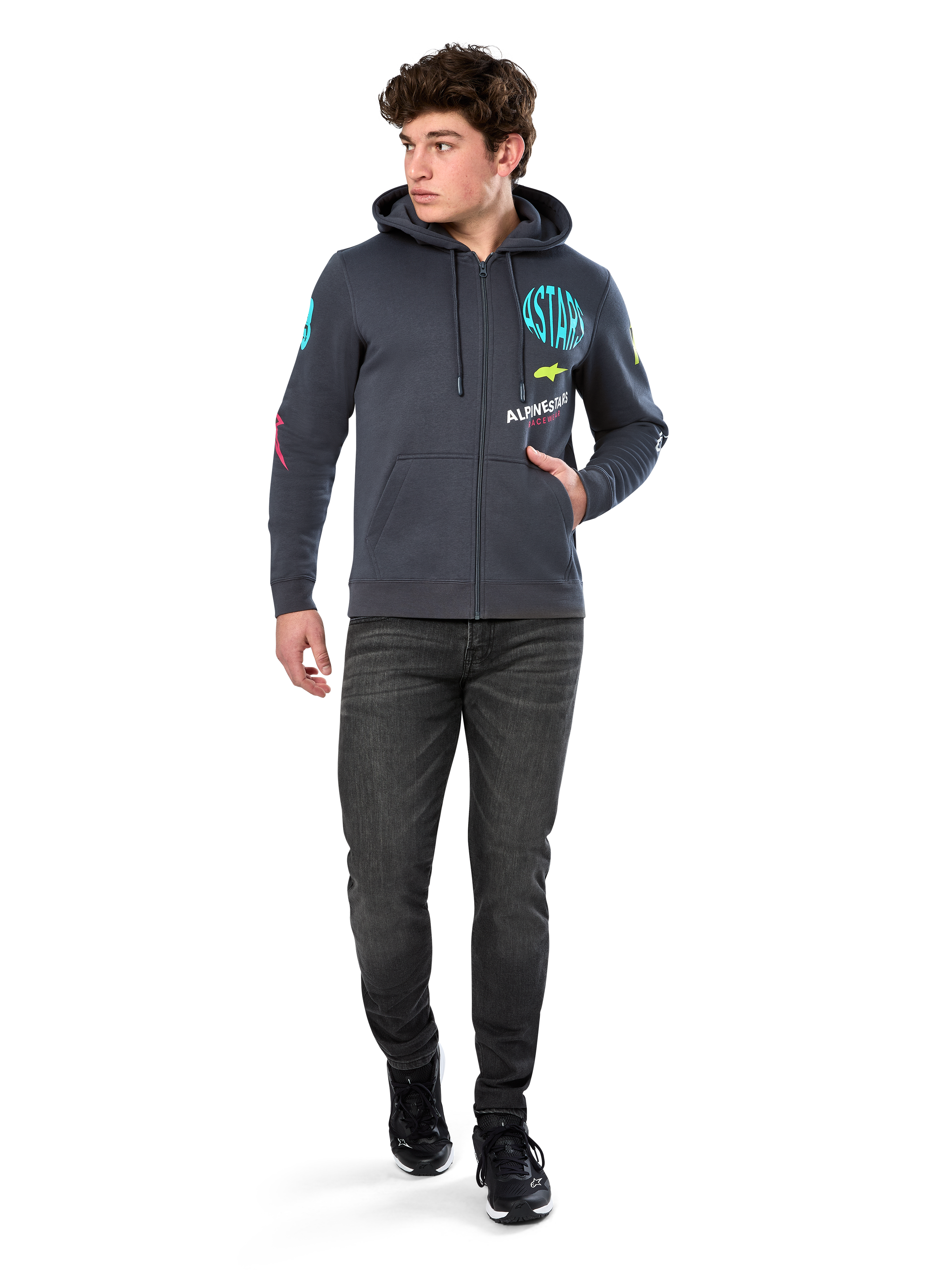 Alpinestars Variegate Hoodie, felpa in pile con zip frontale, grigio Gunmetal, indossata da un modello con jeans neri e sneakers, con marchio 'ASTARS' verde acqua e grafiche logo colorate su maniche e petto, streetwear casual ispirato al motorsport