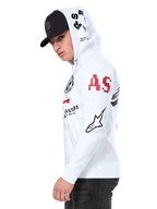 Alpinestars Variegate Hoodie, felpa in pile bianca con zip frontale, grafica multi-logo sulle maniche e sul cappuccio con scritta 'AS' rossa e logo a stella nero, indossata da un uomo con un cappellino nero, streetwear casual ispirato al motorsport