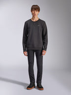 Alpinestars Positive Crew Sweatshirt, felpa girocollo casual nera, piccolo logo bianco sul petto, scollo con cucitura a V, foto a figura intera in studio con modello che indossa pantaloni e sneaker neri, abbigliamento lifestyle ispirato al motorsport