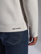 Felpa Alpinestars Positive Crew, Off White, dettaglio ravvicinato di orlo e polsino a coste, con piccolo logo Alpinestars nero, abbigliamento casual ispirato al motorsport