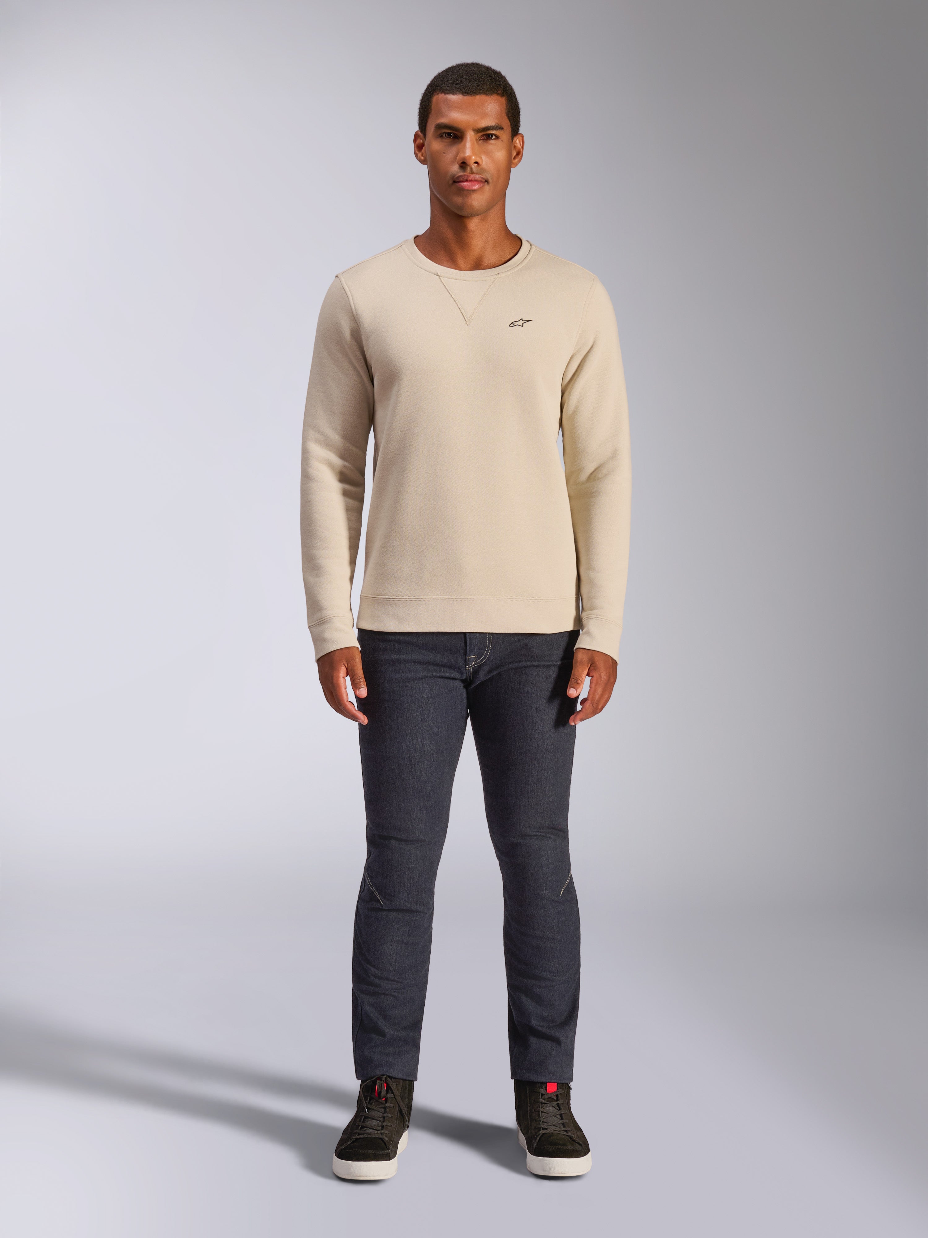 Alpinestars Positive Crew, felpa girocollo Off White, piccolo logo nero sul petto, polsini e orlo a coste, cucitura a triangolo sul collo, streetwear casual motorsport indossata con jeans scuri