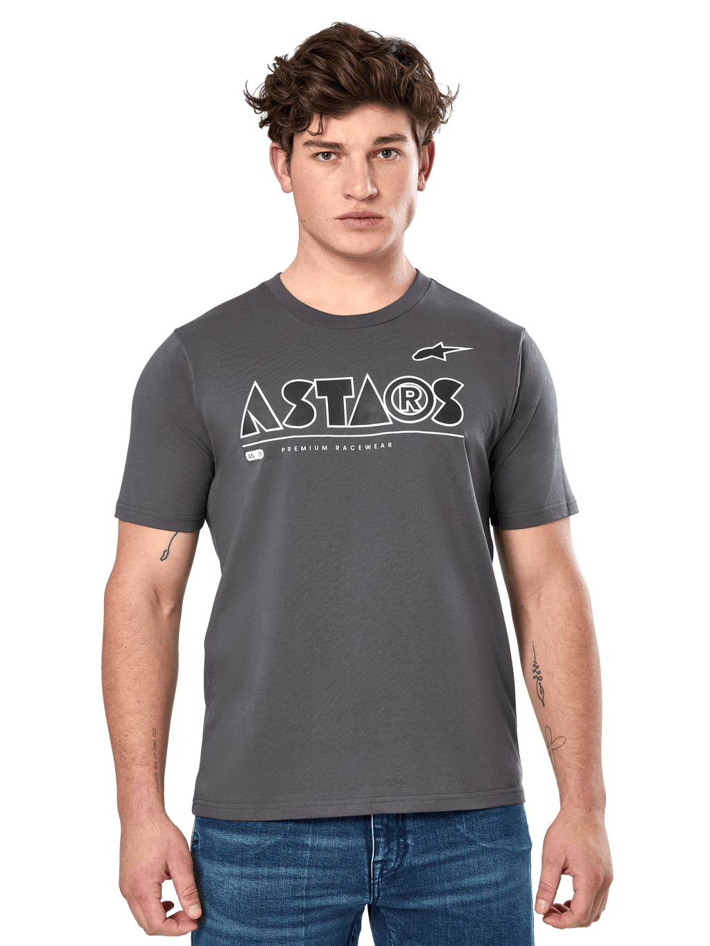 Alpinestars Cereal CSF Tee, t-shirt a maniche corte grigio antracite, indossata da un modello uomo con jeans blu, logo geometrico ASTARS bianco e scritta 'Premium Racewear', abbigliamento lifestyle casual ispirato al motorsport
