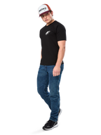 Alpinestars Formulate Csf Tee, maglietta a maniche corte, nero con logo Astars bianco sul petto, indossata da un modello con jeans blu, cappellino bordeaux e bianco e sneakers nere, streetwear casual ispirato al motorsport