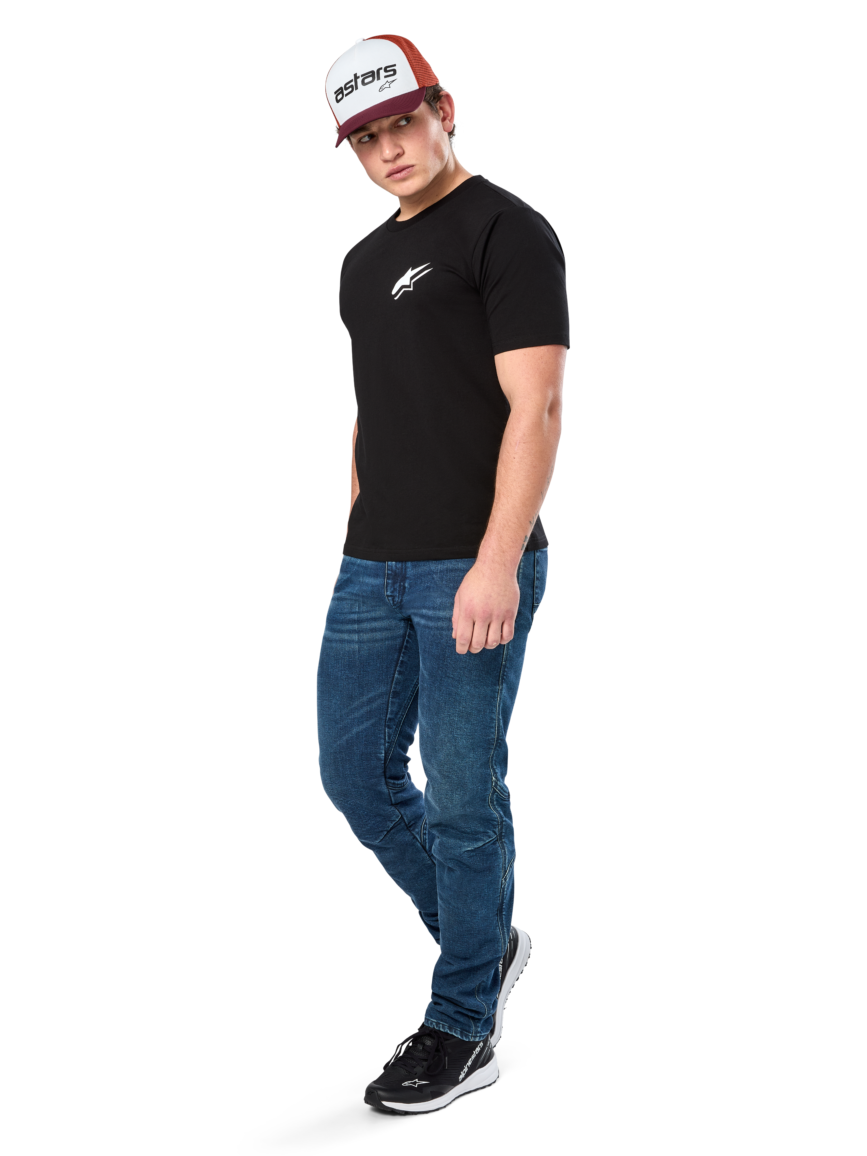 Alpinestars Formulate Csf Tee, maglietta a maniche corte, nero con logo Astars bianco sul petto, indossata da un modello con jeans blu, cappellino bordeaux e bianco e sneakers nere, streetwear casual ispirato al motorsport