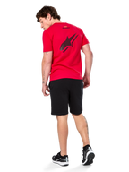 Alpinestars Formulate Csf Tee, maglietta a maniche corte, rosso, grande logo Astars traforato nero sul retro, indossata con pantaloncini neri e sneakers, streetwear casual ispirato al motorsport