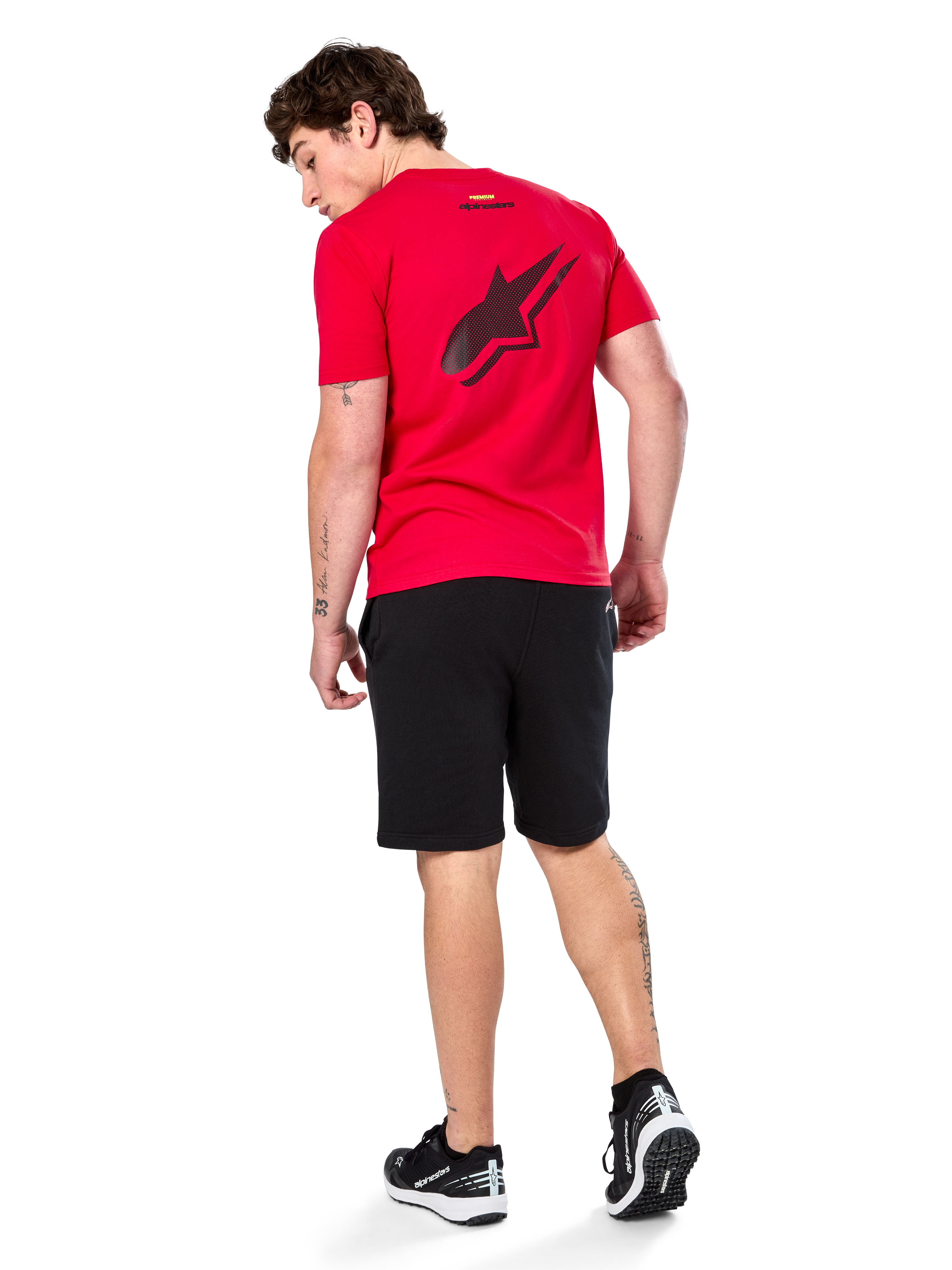 Alpinestars Formulate Csf Tee, maglietta a maniche corte, rosso, grande logo Astars traforato nero sul retro, indossata con pantaloncini neri e sneakers, streetwear casual ispirato al motorsport