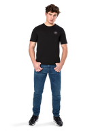 T-shirt Alpinestars Dot Carbon CSF, maglietta a maniche corte, nero, piccolo logo circolare Astars Dot sul petto, indossata con jeans blu e sneakers nere, streetwear casual ispirato al motorsport
