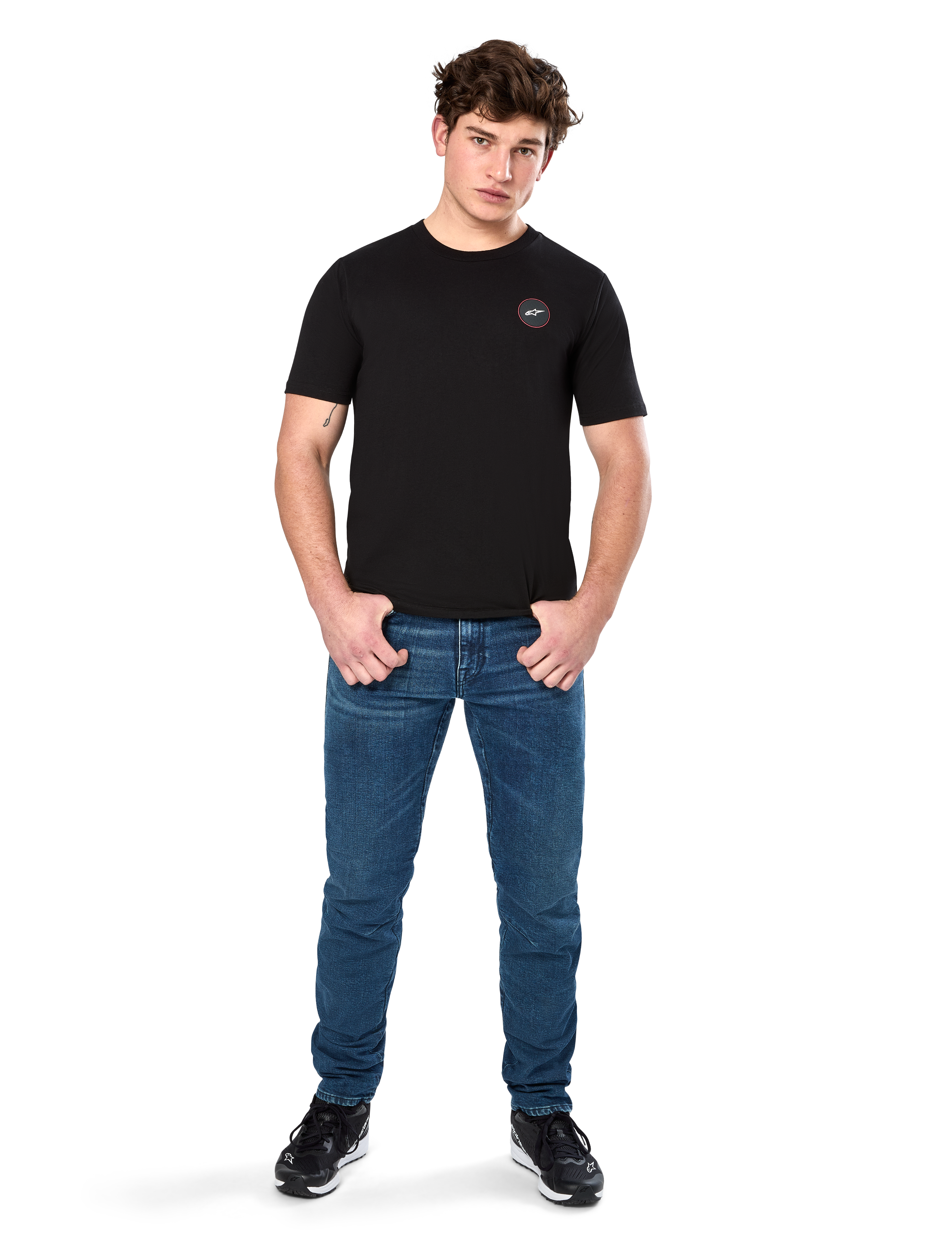 T-shirt Alpinestars Dot Carbon CSF, maglietta a maniche corte, nero, piccolo logo circolare Astars Dot sul petto, indossata con jeans blu e sneakers nere, streetwear casual ispirato al motorsport