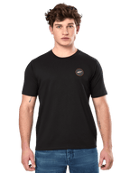 Alpinestars Dot Carbon CSF Tee, maglietta a maniche corte, nero, piccolo logo circolare sul petto con Astar bianca e bordo rosso, indossata da un modello con jeans blu, streetwear casual motorsport