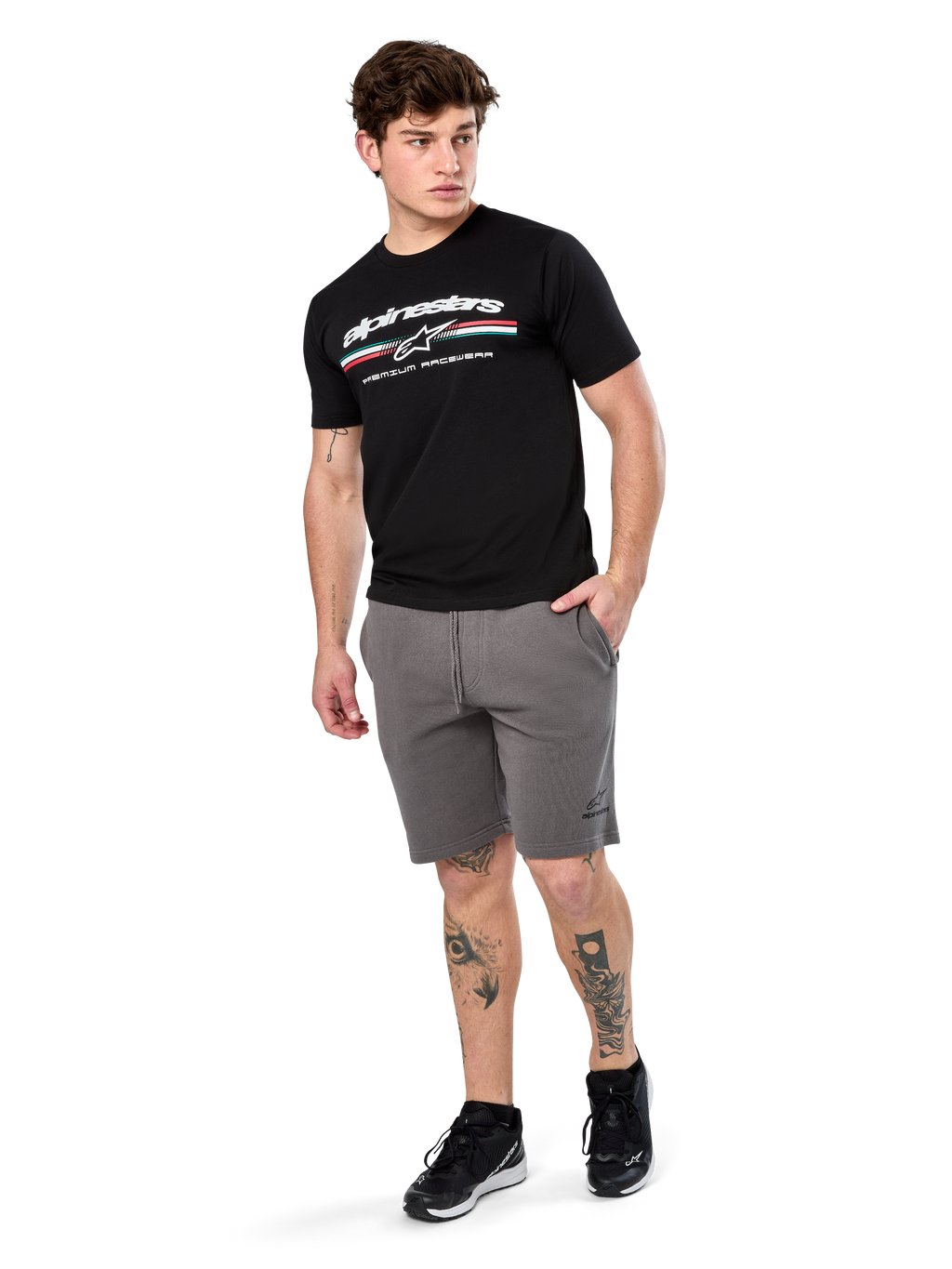 Alpinestars Prevail Csf Tee, maglietta a maniche corte, nero, logo Alpinestars bianco con striscia tricolore stile paddock, indossata con pantaloncini grigi e sneakers nere, abbigliamento casual motorsport streetwear