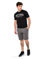 Alpinestars Prevail Csf Tee, maglietta a maniche corte, nero, logo Alpinestars bianco con striscia tricolore stile paddock, indossata con pantaloncini grigi e sneakers nere, abbigliamento casual motorsport streetwear