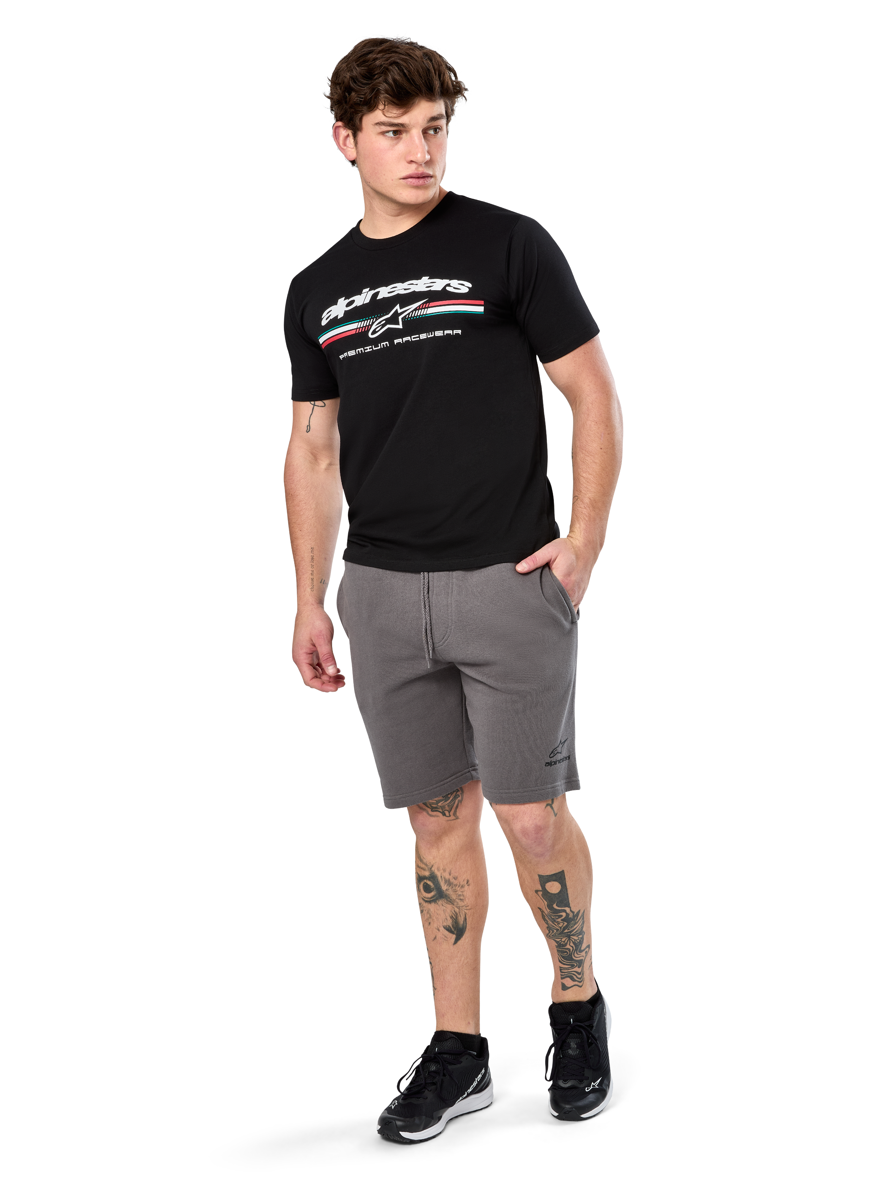 Alpinestars Prevail Csf Tee, maglietta a maniche corte, nero, logo Alpinestars bianco con striscia tricolore stile paddock, indossata con pantaloncini grigi e sneakers nere, abbigliamento casual motorsport streetwear