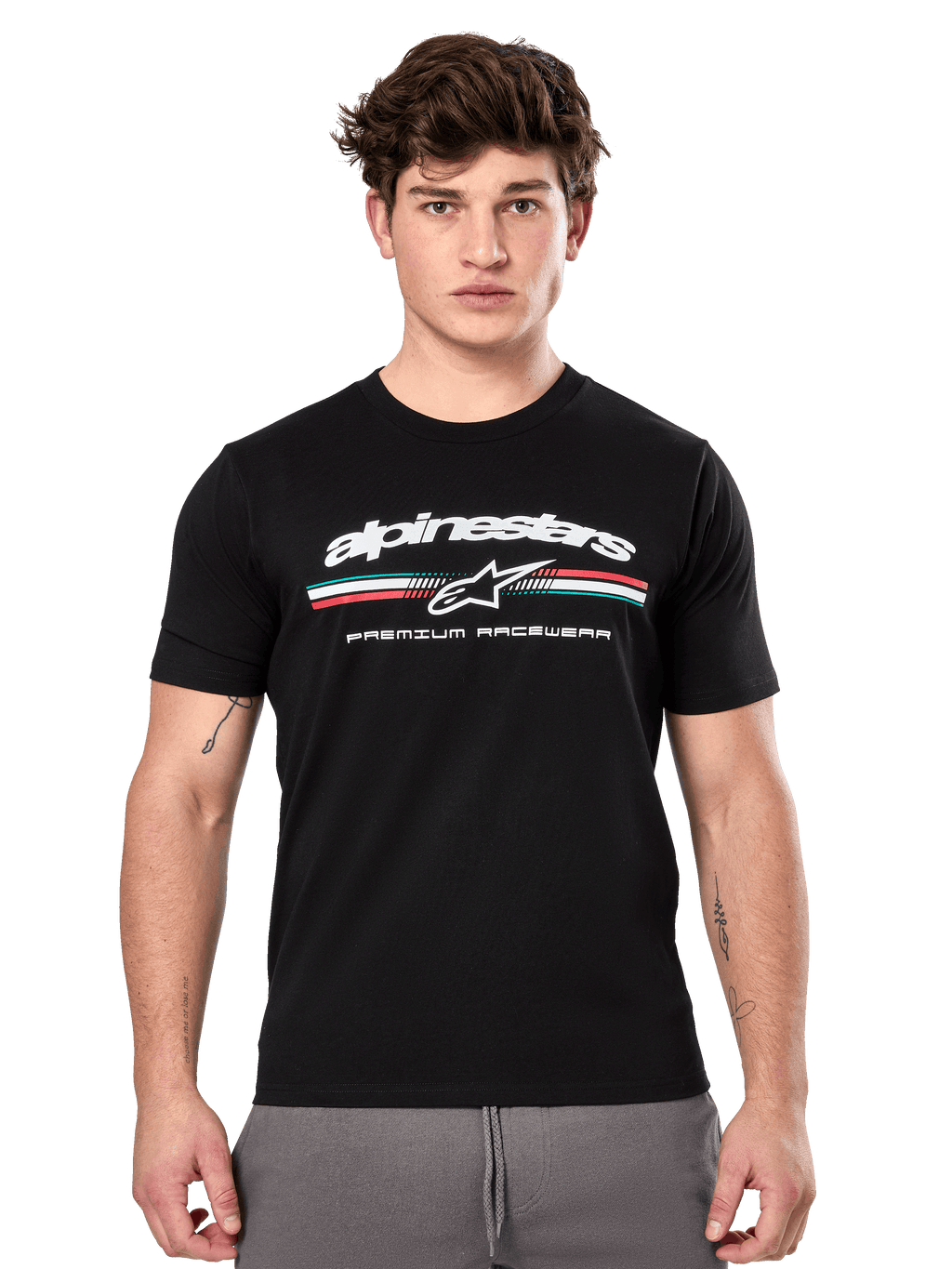 Alpinestars Prevail CSF Tee, maglietta nera a maniche corte indossata da un modello, con logo bianco, striscia tricolore e grafica "PREMIUM RACEWEAR", streetwear casual motorsport